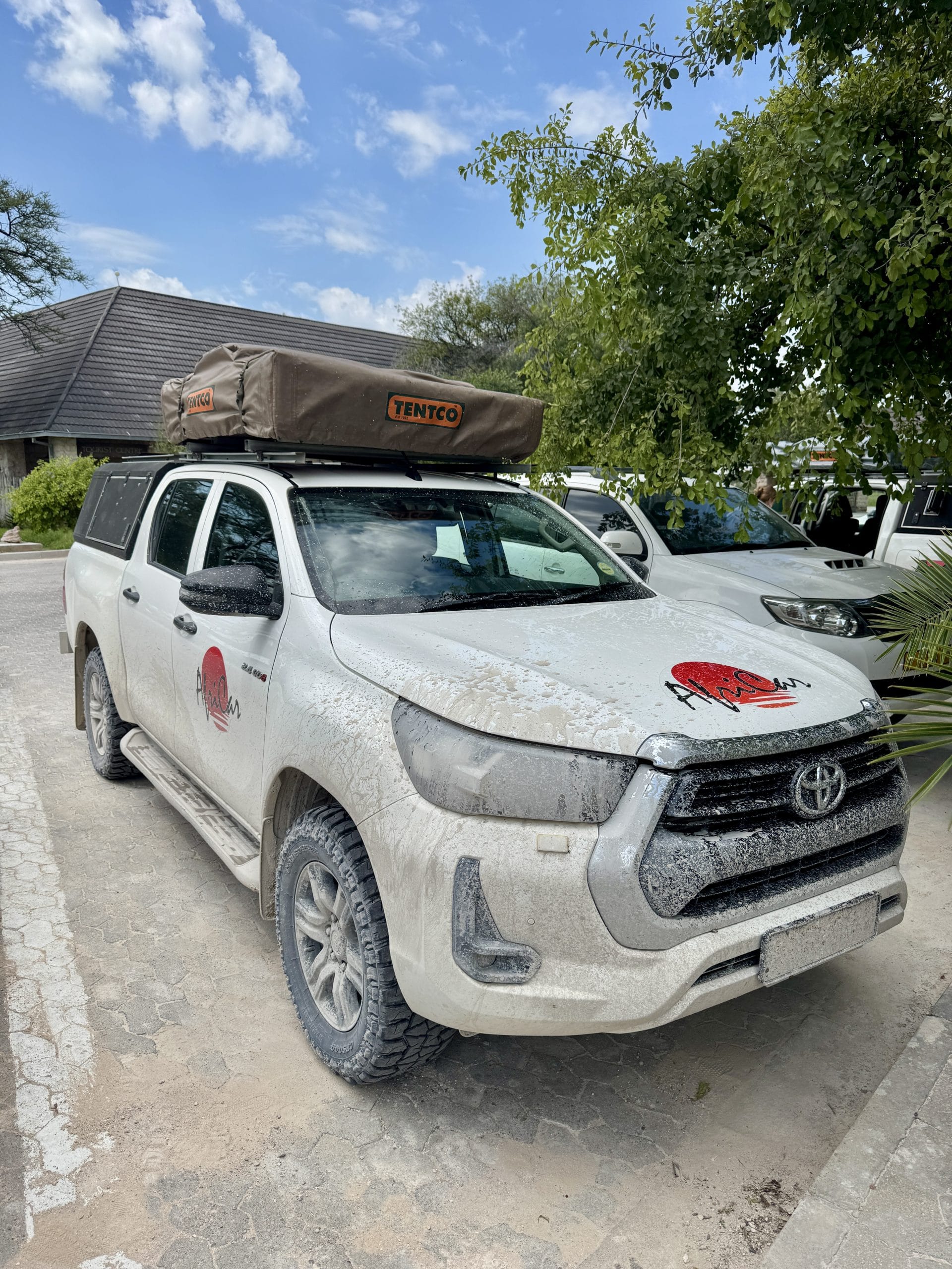 Toyota Hilux 4x4 met daktent van Tentco en Airic Travel logo, stoffig van de gravelwegen tijdens een roadtrip door Namibië.